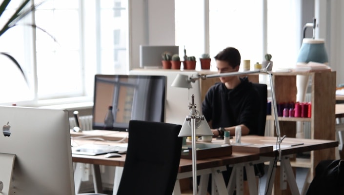 photo of office with desktops and one guy working